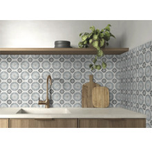 Küchenrückwand mit gemusterten Fliesen im floralen Zirkeldesign, Bronze-Armatur, weißes Spülbecken und Holzregal.