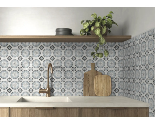 Küchenrückwand mit gemusterten Fliesen im floralen Zirkeldesign, Bronze-Armatur, weißes Spülbecken und Holzregal.