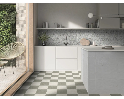 Helle moderne Küche mit schachbrettartigen Bodenfliesen, weißen Schränken, gesprenkeltem Fliesenspiegel und gefliester Kücheninsel.