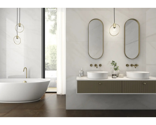 Modernes Badezimmer mit freistehender Badewanne, hängendem Waschtisch, goldenen Armaturen, ovalen Spiegeln und Fliesen in Marmoroptik.