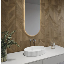 Modernes Badezimmer mit Wandfliesen in Holzoptik und geometrischem Muster, weißem Aufsatzwaschbecken und beleuchtetem ovalem Spiegel.