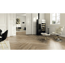 Helles Wohnzimmer mit Laminatboden in Fischgrät-Optik, schwarzem Kaminofen, weißem Sessel und Wandpaneelen.