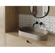 Modernes Badezimmer mit ovalem Aufsatzwaschbecken auf einem Holzunterschrank, schwarzer Wandarmatur und gemusterten Fliesen.