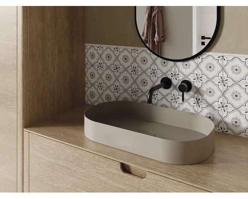 Modernes Badezimmer mit ovalem Aufsatzwaschbecken auf einem Holzunterschrank, schwarzer Wandarmatur und gemusterten Fliesen.