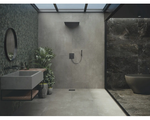 Modernes Badezimmer mit grauen Fliesen, begehbarer Dusche, Betonwaschbecken, schwarzem Rundspiegel und freistehender Badewanne.
