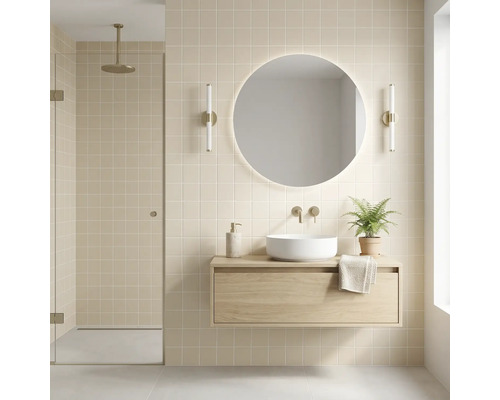 Modernes Badezimmer mit schwebendem Waschtischunterschrank aus Holz, weißem Aufsatzbecken, beleuchtetem Rundspiegel und beigen Fliesen.