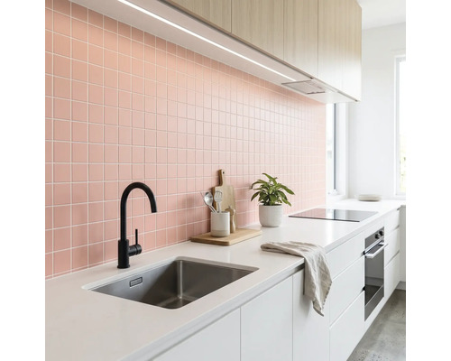 Moderne helle Küche mit rosa Fliesenspiegel, weißer Arbeitsplatte, Edelstahlspüle, schwarzer Armatur und Holzschränken.