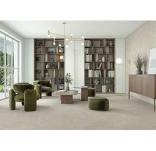 Helles Wohnzimmer mit großformatigen Bodenfliesen in Steinoptik, grünen Polstersesseln, Holzregalen und moderner Deckenleuchte.