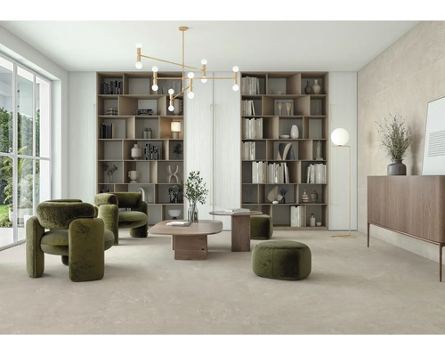 Helles Wohnzimmer mit großformatigen Bodenfliesen in Steinoptik, grünen Polstersesseln, Holzregalen und moderner Deckenleuchte.