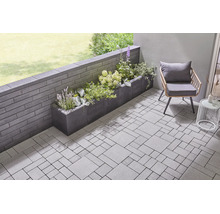 Moderne Terrasse mit Pflastersteinen, Gartenmauer aus Betonsteinen und einem bepflanzten Pflanzkasten.