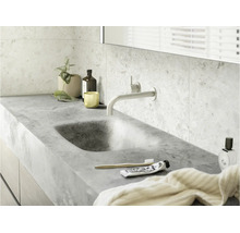 Modernes Badezimmer mit integriertem Naturstein-Waschbecken, wandmontierter Armatur und hellen Terrazzo-Wandfliesen.