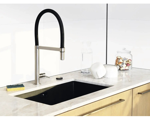 Moderne Küche mit schwarzer Einbauspüle, Armatur mit flexiblem Auslauf, Arbeitsplatte in Marmoroptik und Holzunterschränken.