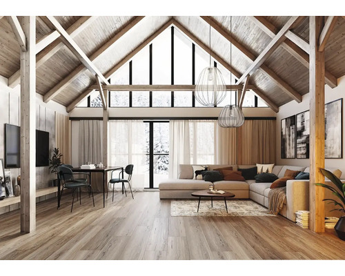 Großzügiges Wohnzimmer mit hohem Giebeldach, sichtbaren Holzbalken, grauem Ecksofa, Essbereich und hellem Holzboden im modernen Landhausstil.