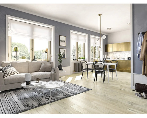 Heller Wohnbereich mit Laminatboden, beigem Sofa, gemustertem Teppich und angrenzendem Essbereich mit weißem Tisch und schwarzen Stühlen.