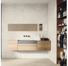 Moderner Badezimmerbereich mit wandhängendem Waschtisch aus hellem Holz, integriertem Becken und Wandarmatur. Rechts ein Regal mit Handtüchern.