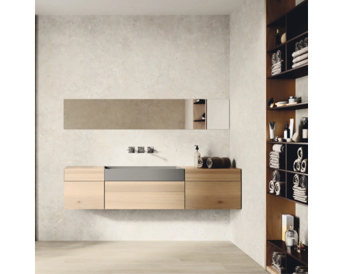 Moderner Badezimmerbereich mit wandhängendem Waschtisch aus hellem Holz, integriertem Becken und Wandarmatur. Rechts ein Regal mit Handtüchern.