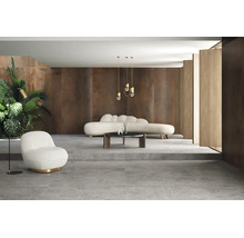 Moderner Wohnraum mit großformatigen grauen Bodenfliesen, braunen Wandpaneelen in Rostoptik, einem geschwungenen weißen Sofa und Sessel.