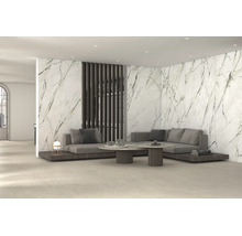 Modernes Wohnzimmer mit großformatigen Wandfliesen in Marmoroptik, grauem Sofa und runden Couchtischen.