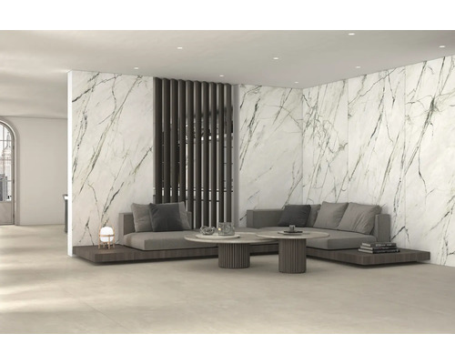 Modernes Wohnzimmer mit großformatigen Wandfliesen in Marmoroptik, grauem Sofa und runden Couchtischen.