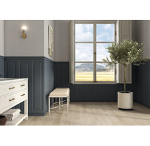 Heller Raum mit blauer Wandtäfelung, Fenster mit Bergblick, hellem Holzboden, weißem Waschtisch und Olivenbaum im Topf.