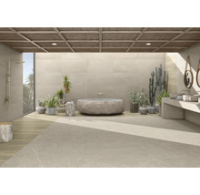 Helles Badezimmer mit großformatigen Bodenfliesen in Steinoptik, einer freistehenden Steinbadewanne, Regendusche und mediterranen Pflanzen.