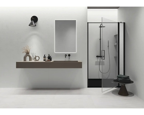 Modernes minimalistisches Badezimmer mit schwebendem Waschtisch, beleuchtetem Spiegel, schwarzer Armatur und Dusche mit schwarzem Rahmen.