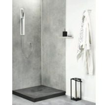 Moderne Duschecke mit Betonoptik Duschwand, bodengleicher Duschwanne, Handbrause und Ablageregal in einem zeitgenössischen Badezimmer.