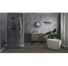 Modernes Badezimmer mit Dusche, Waschbeckenunterschrank in Holzoptik, rundem Spiegel und freistehender Badewanne vor marmorierter Wandverkleidung.