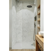 Moderne begehbare Dusche mit Steinfliesen in Natursteinoptik und einer Regendusche aus dunklem Metall in einem hellen Badezimmer.