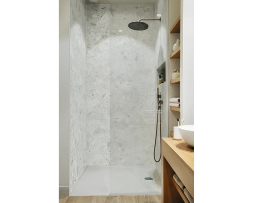 Moderne begehbare Dusche mit Steinfliesen in Natursteinoptik und einer Regendusche aus dunklem Metall in einem hellen Badezimmer.