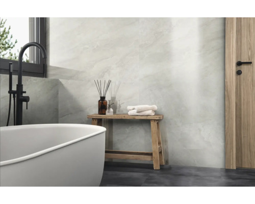 Modernes Badezimmer mit hellen Marmoroptik Wandfliesen, freistehender Badewanne, schwarzer Armatur, Holzhocker und Holztür.