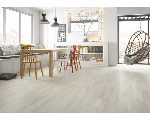 Heller, moderner Wohnraum mit Bodenbelag in heller Holzoptik, Holzesstisch mit farbigen Stühlen und einem Hängesessel.