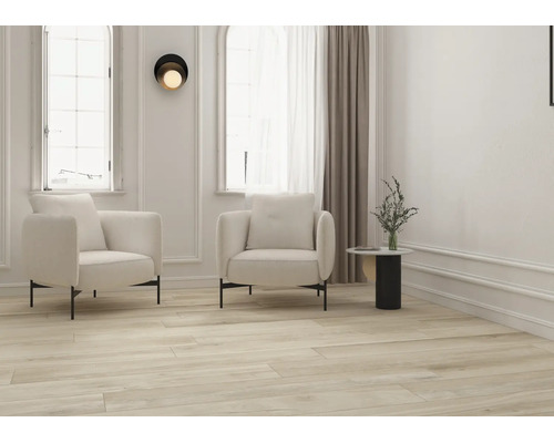 Helles modernes Wohnzimmer mit hellem Bodenbelag in Holzoptik, zwei cremefarbenen Sesseln, Beistelltisch und großen Fenstern mit Wandleisten.