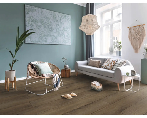 Modernes Wohnzimmer mit dunklem Bodenbelag in Holzoptik, grauem Sofa, Korbsessel, Zimmerpflanze und hellem Ambiente.