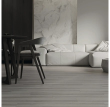 Moderner Wohnbereich mit Bodenbelag in Holzoptik, Esszimmermöbeln und modularem Sofa vor einer strukturierten Wand.