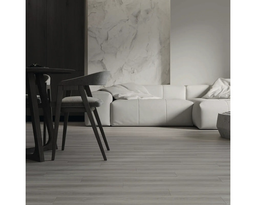 Moderner Wohnbereich mit Bodenbelag in Holzoptik, Esszimmermöbeln und modularem Sofa vor einer strukturierten Wand.