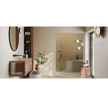 Modernes, helles Badezimmer mit wandhängendem Waschtisch, rundem Spiegel und schwarzen Armaturen. Im Hintergrund eine freistehende Badewanne.