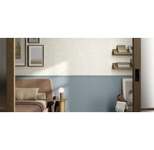 Wandgestaltung im Schlafzimmer mit weißen Fliesen in Terrazzo-Optik oben und hellblauen geriffelten Wandfliesen unten.