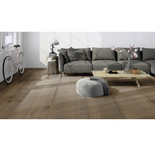 Modernes Wohnzimmer mit Parkettboden in Eichenoptik, grauem Sofa und hellem Holztisch in lichtdurchflutetem Ambiente.