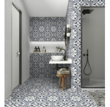 Modernes Badezimmer mit gemusterten Zementfliesen an Boden und Wänden, weißem Aufsatzwaschbecken und einer begehbaren Dusche mit schwarzen Armaturen.