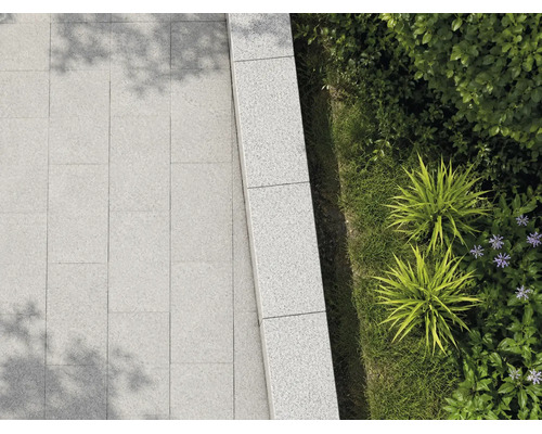 Terrassenplatten und Mauersteine aus Granit im Außenbereich mit Bepflanzung.