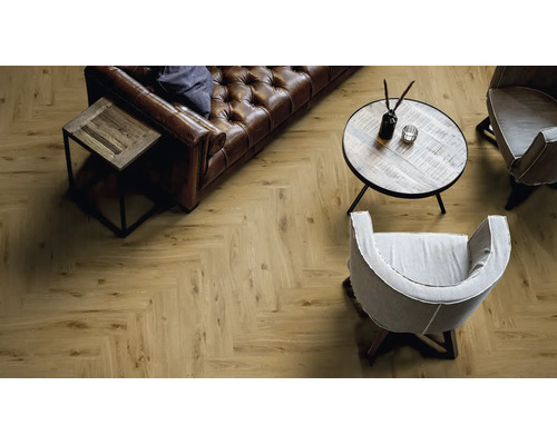 Wohnzimmer mit Fischgrät Laminatboden in Holzoptik, Ledersofa, zwei Sesseln und einem runden Holztisch in einer modernen Wohnatmosphäre.