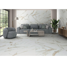 Modernes Wohnzimmer mit großformatigen Boden- und Wandfliesen in Marmoroptik mit goldener Maserung, grauem Sofa und heller Atmosphäre.