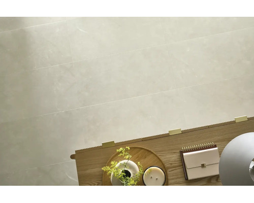 Großformatige Wandfliesen mit dezenter Steinoptik in einem Wohnraum mit Holztisch und dekorativen Accessoires.