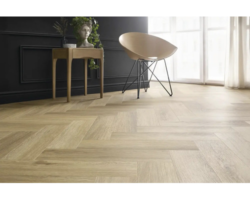Heller Holzoptik Bodenbelag in Fischgrät Verlegemuster in einem modern eingerichteten Raum mit Stuhl und Beistelltisch.