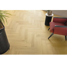Heller Holzoptik Laminatboden in Fischgrät Verlegemuster in einem modern eingerichteten Wohnbereich mit Sessel und Beistelltisch.