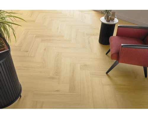 Heller Holzoptik Laminatboden in Fischgrät Verlegemuster in einem modern eingerichteten Wohnbereich mit Sessel und Beistelltisch.