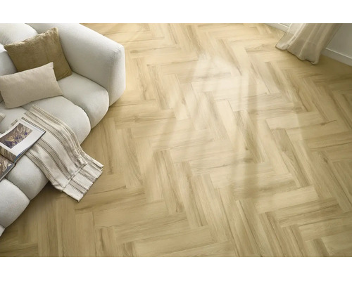 Heller Holzoptik Bodenbelag in Fischgrät Verlegemuster in einem Wohnraum mit Sofa.