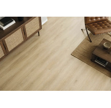 Wohnraum mit hellem Holzoptik Laminatboden, Sideboard mit Geflechtfront, Ledersessel und Couchtisch auf einem Jute-Teppich.