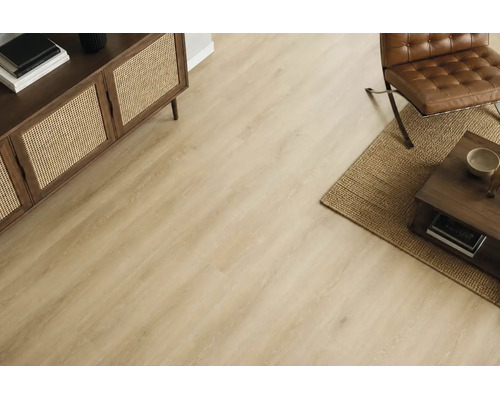 Wohnraum mit hellem Holzoptik Laminatboden, Sideboard mit Geflechtfront, Ledersessel und Couchtisch auf einem Jute-Teppich.